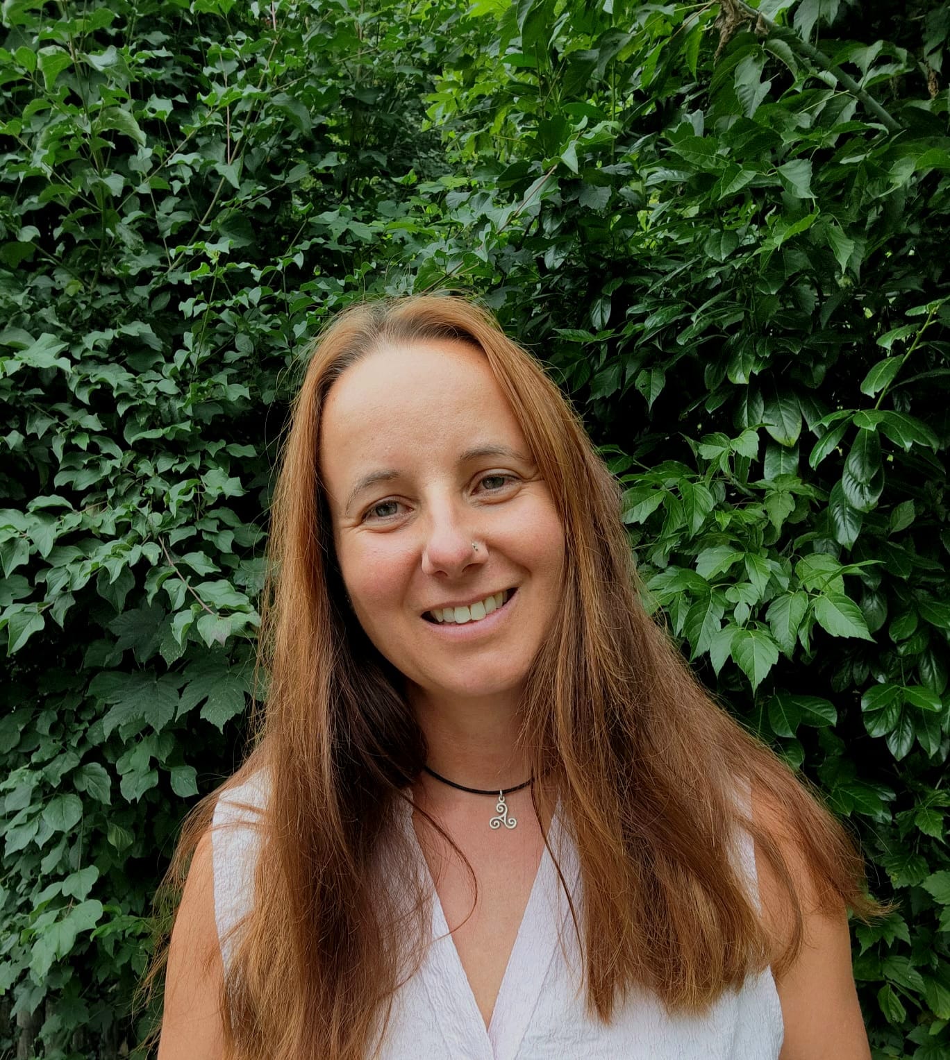 Portraitfoto von Ursula Brunnbauer vor einer grünen Hecke